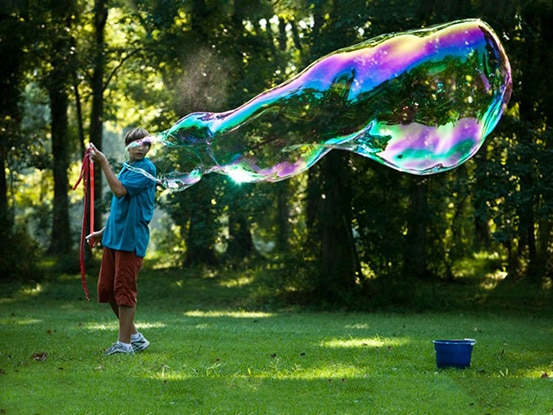 Kids playing with bubbles in the woods.