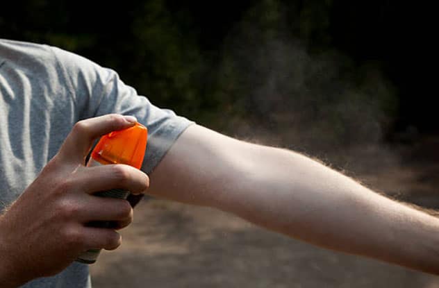 Spraying on bug repellent while camping.