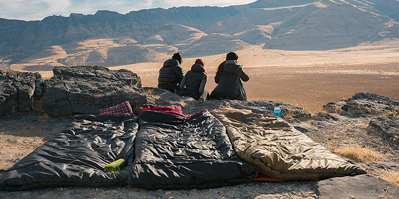 A group of 3 people outdoors in the desert camping.